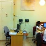 עמדת פקידה במשרד קופת חולים היושבת בצמידות אל לוח חשמל מקומי